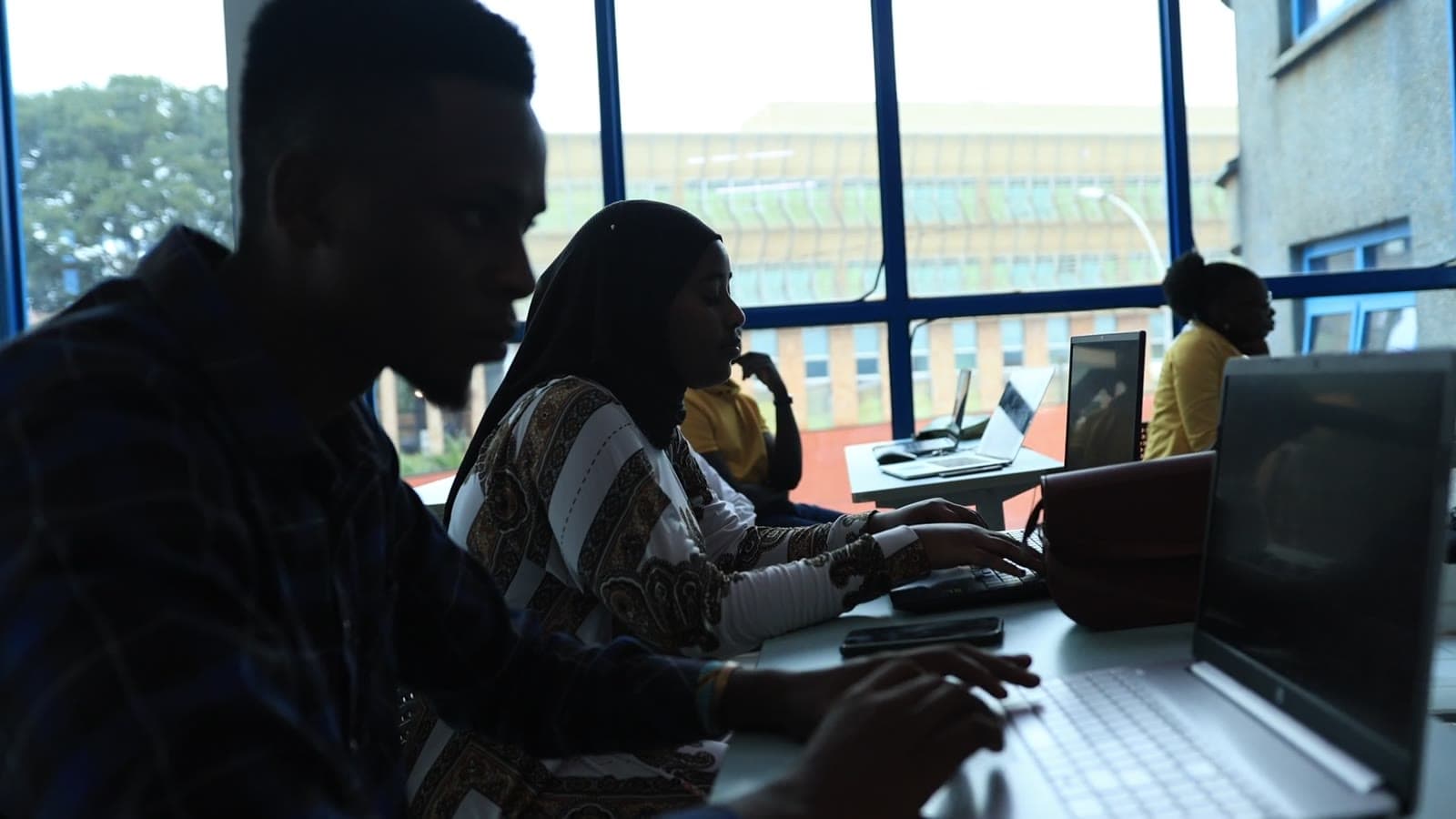 Learners working together at laptops in a bright classroom